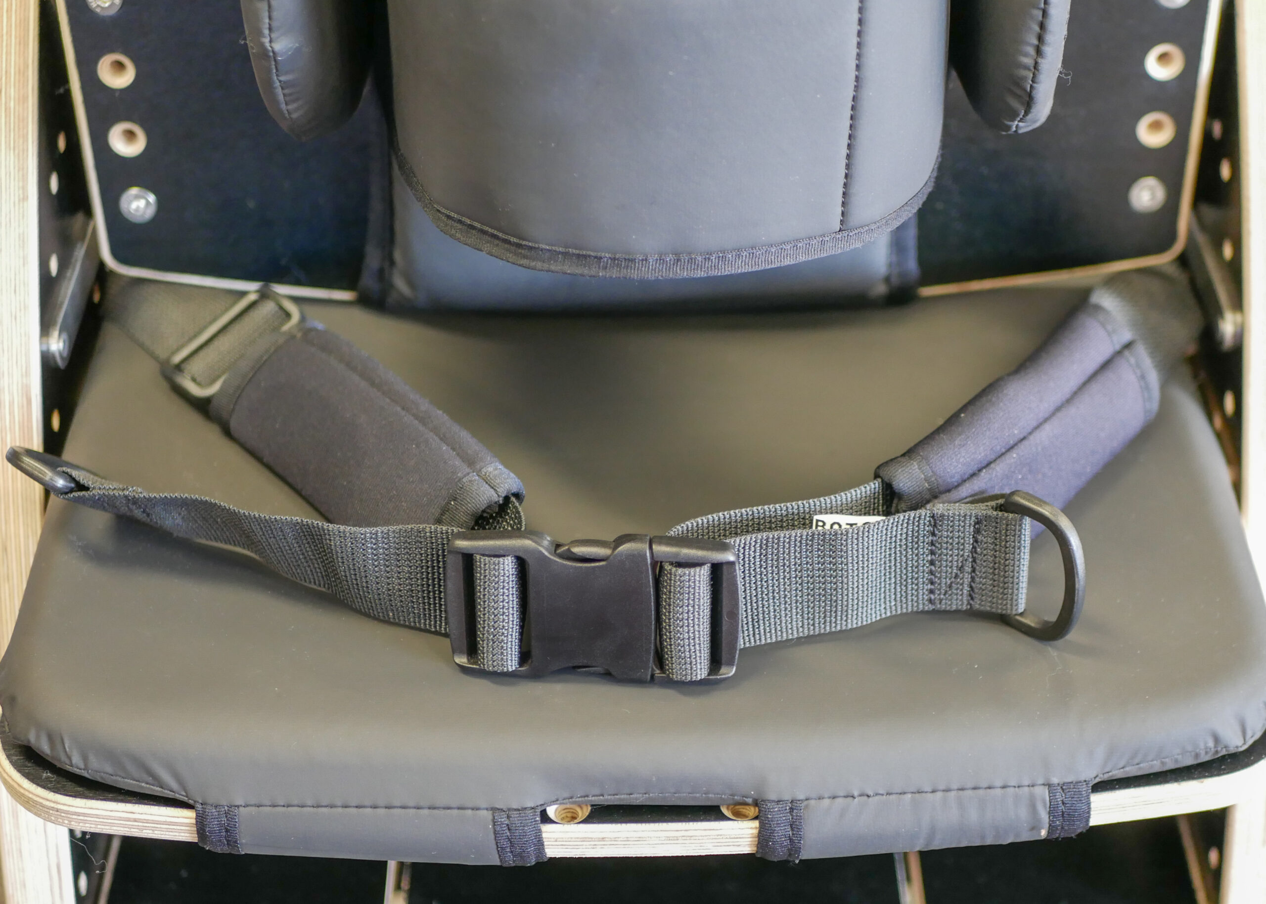 Close-up of the Zeat Seat padded seat with adjustable safety harness and buckle for secure positioning.