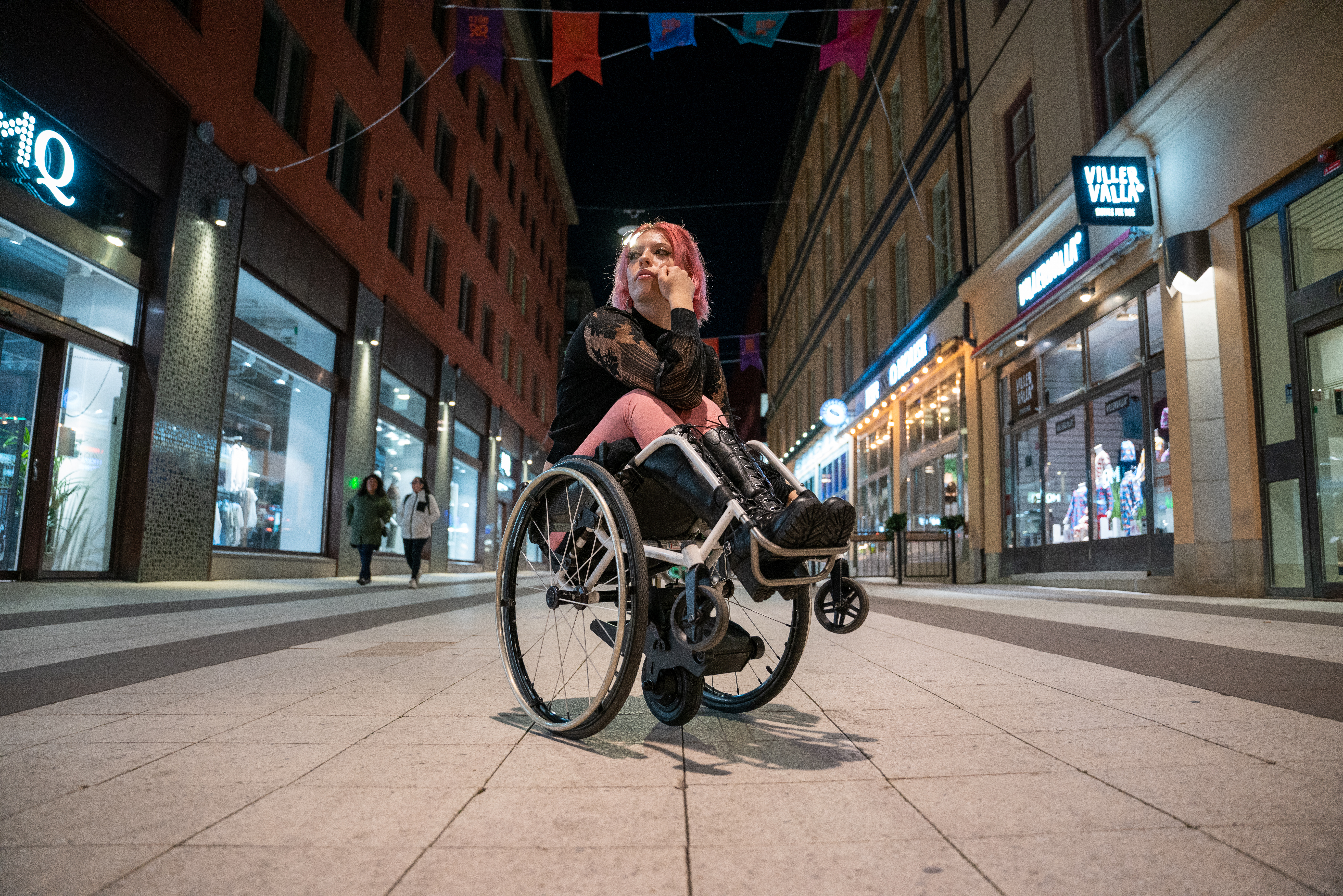 Manual wheelchair with Yomper power assist used on an accessible pedestrian city in a city at night.