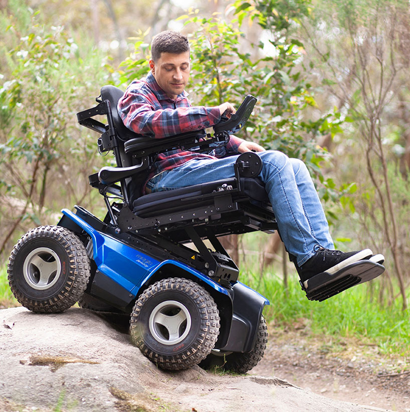 Person using Magic Mobility XT4 wheelchair outdoors on rocky slope
