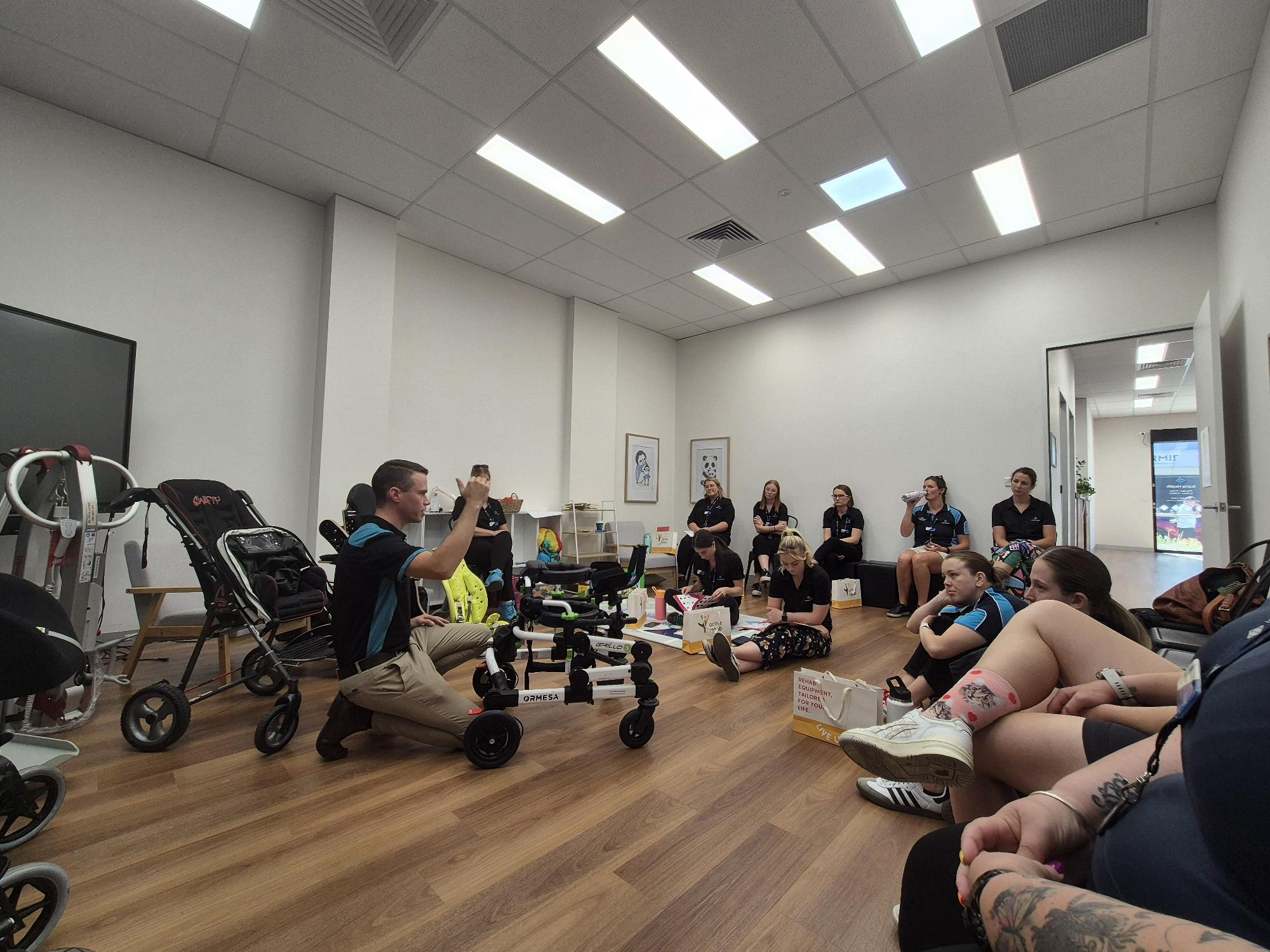 Group training session with therapist demonstrating pediatric mobility equipment indoors